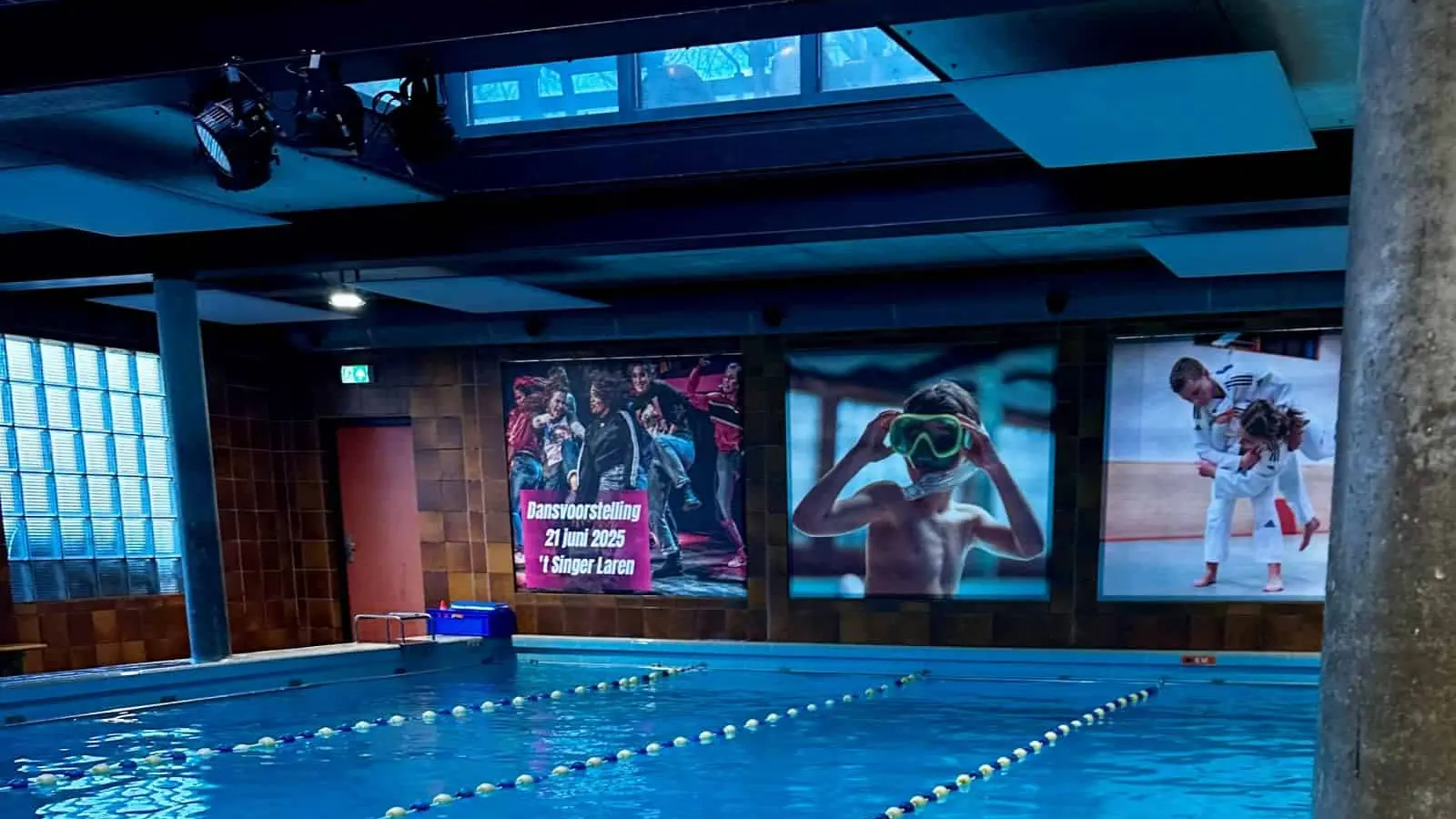 Het overdekte lesbad bij Rebel Sport in Huizen — helder blauw water met baanlijnen.