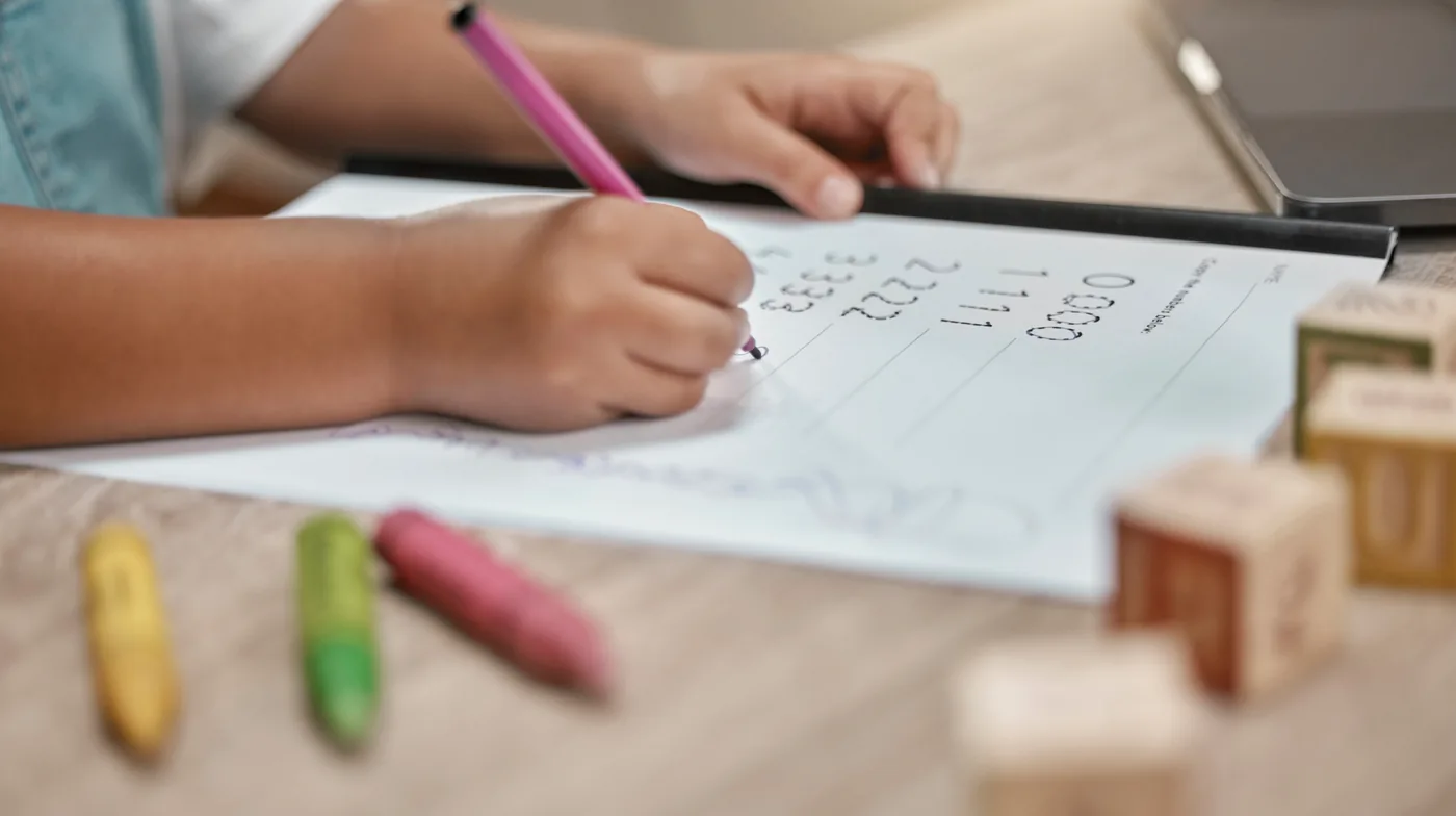 Een kind werkt met een pen aan een werkblad op de keukentafel